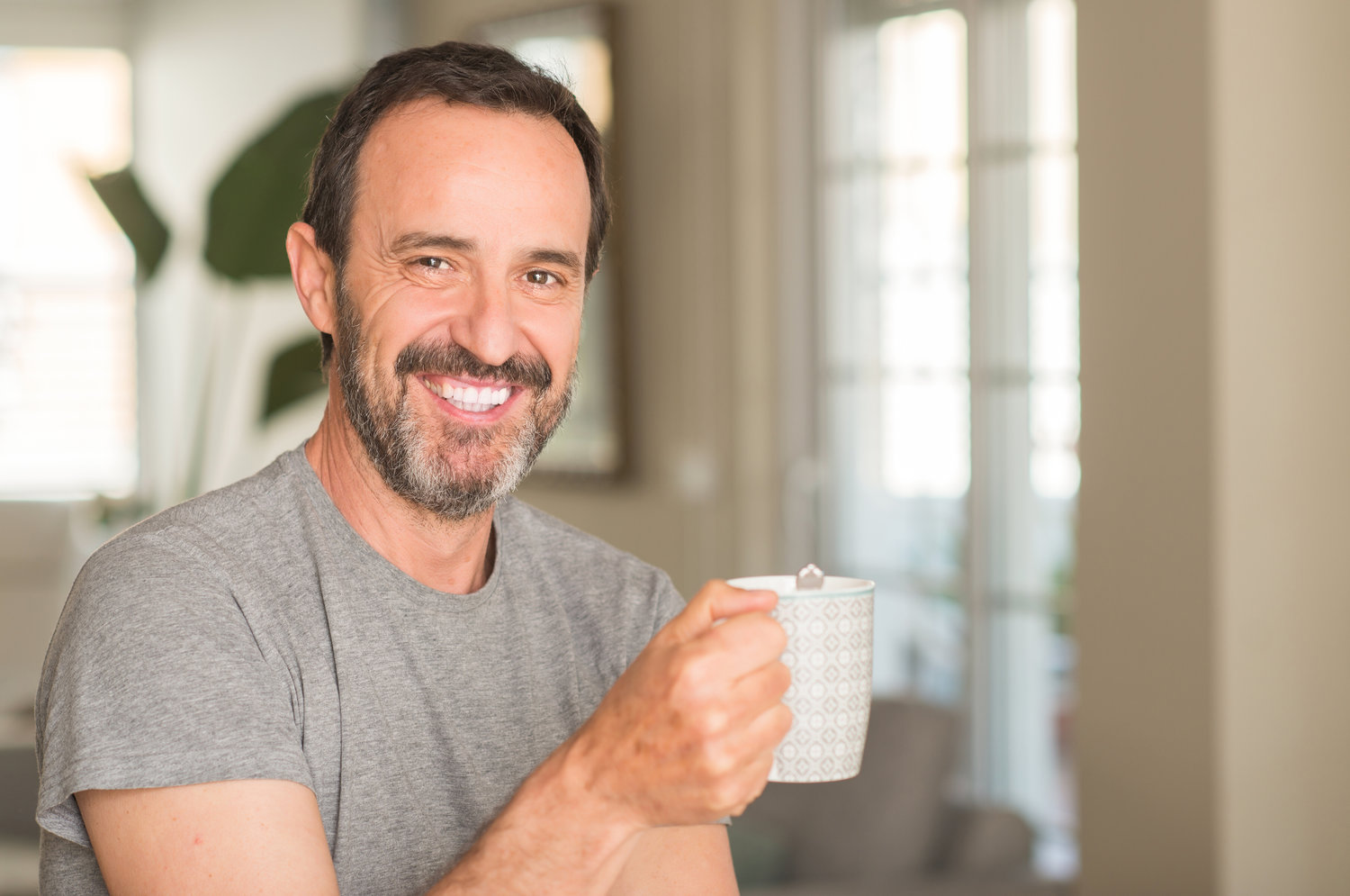 Middle age man drinking coffee in a cup with a happy face standi